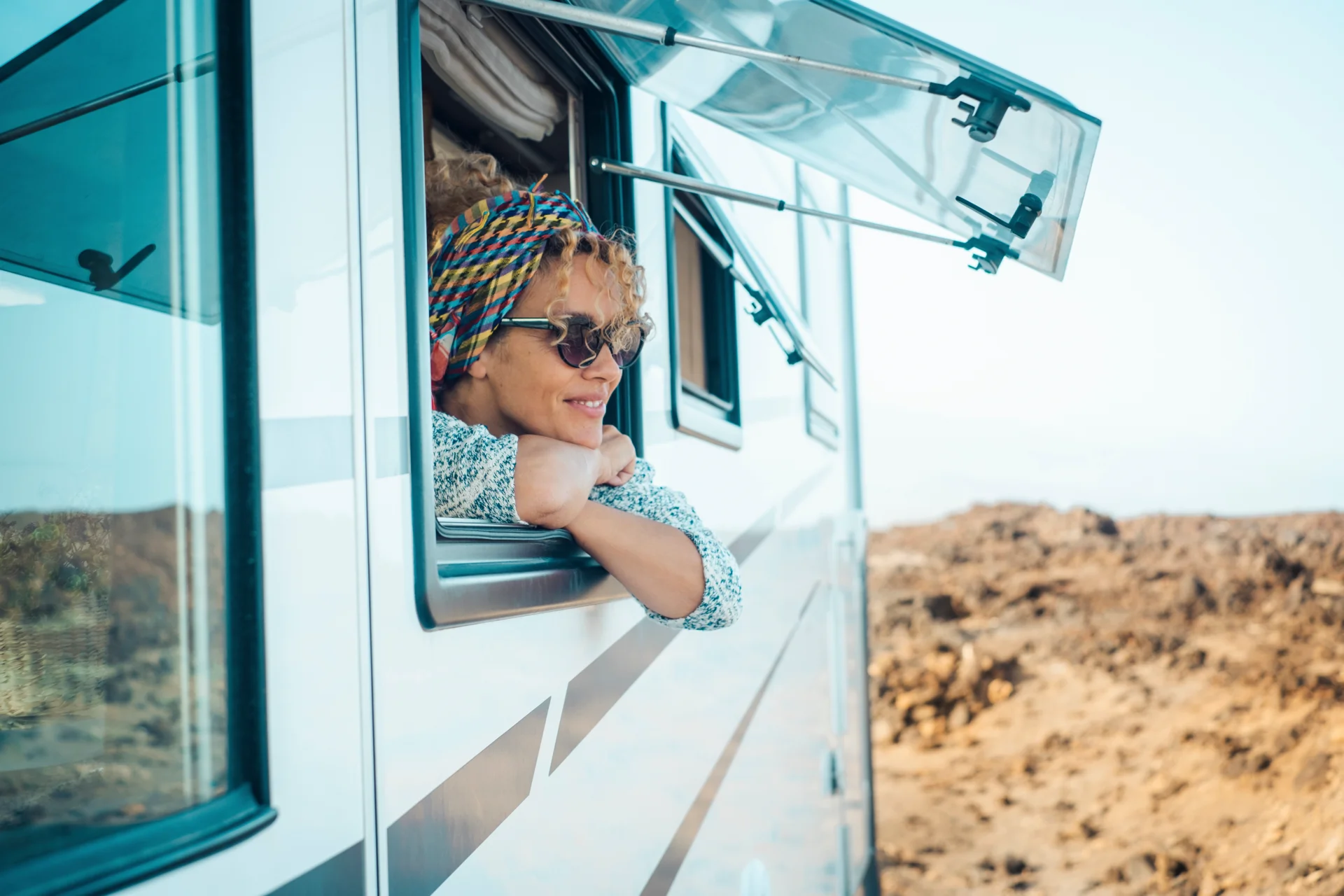 Traveler leaning out of a motorhome window on a desert road